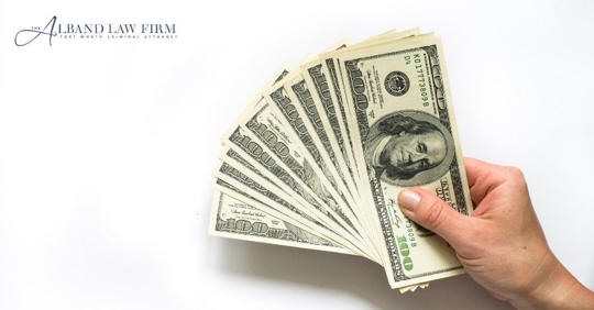 person's hand holding dollars