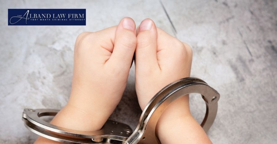 young person's hands in handcuffs